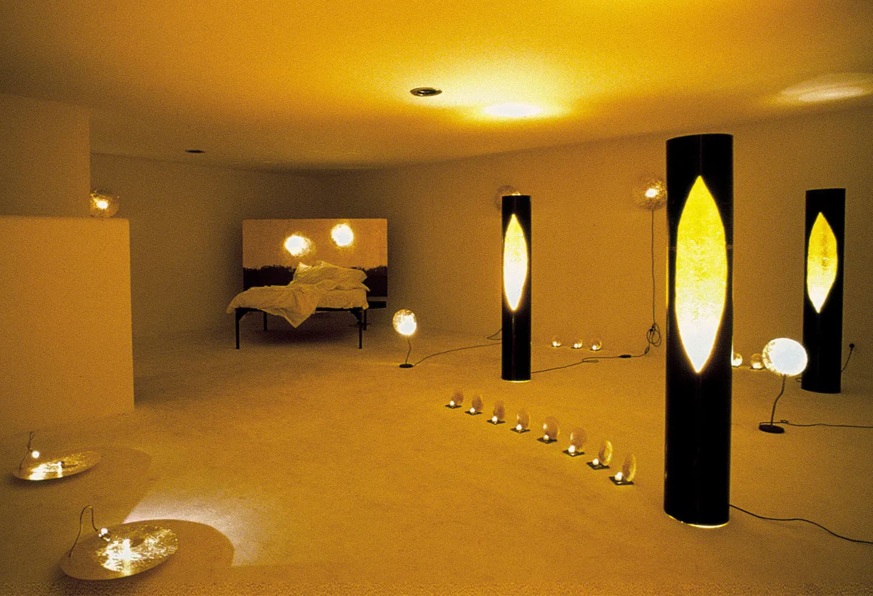 <p>Installation „Luce d&#8217;Oro“ (goldene Lichter) für den Dilmos-Showroom in Mailand mit blattvergoldeten Eisensäulen, deren Reflexionen aus einem Spalt auf der Vorderseite austreten. Bei dieser Gelegenheit wurde auch die limitierte Auflage „Letto Sogni d&#8217;oro“ (Bett für süße/goldene Träume) vorgestellt, bei der das große eiserne Kopfteil zu mehr als der Hälfte mit Blattgold bedeckt war. Eines dieser Exemplare wurde von Claudio Baglioni erworben.</p>
