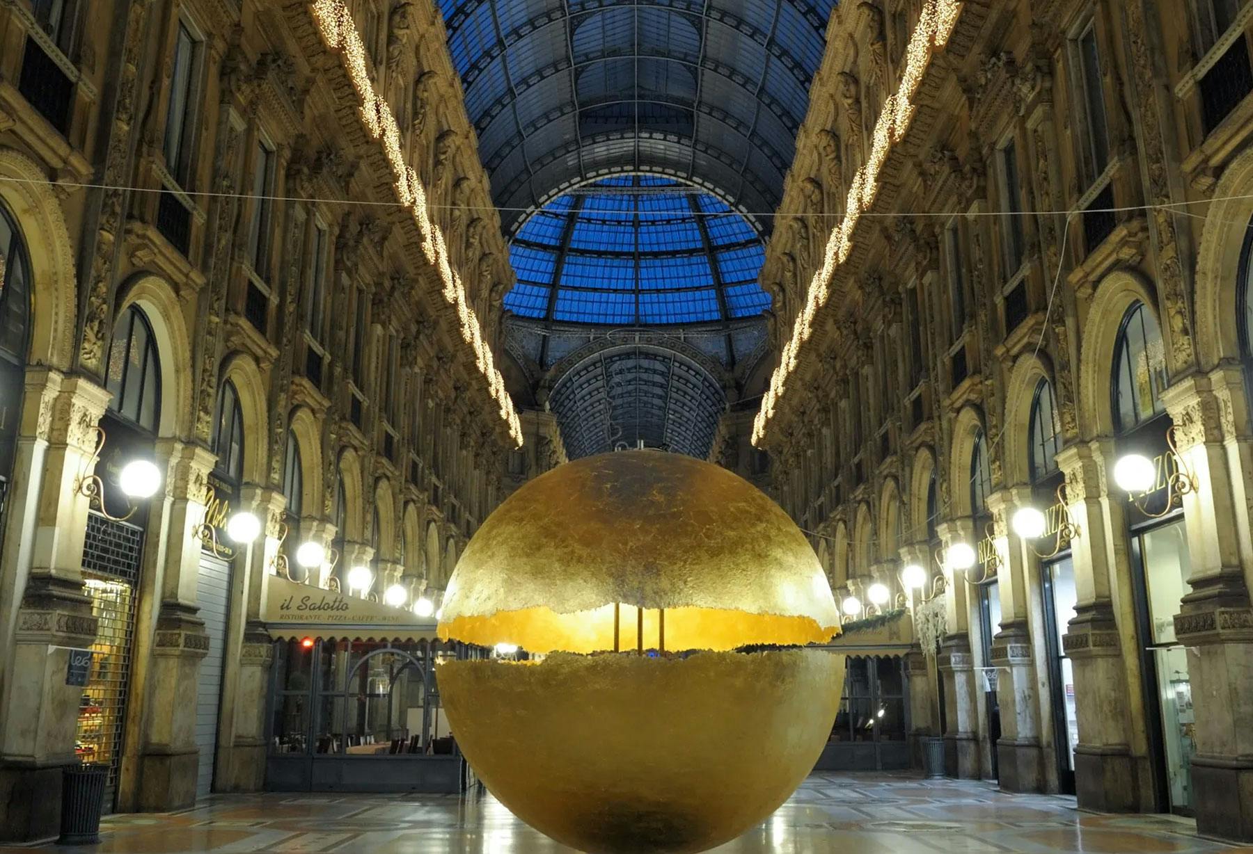 <p>Installation « PostKrisi » dans la Galleria Vittorio Emanuele à Milan : une grande sphère posée à même le sol, lumineuse et imposante, est entièrement recouverte en feuille d’or dans une composition qui allie la valeur du passé à la technologie actuelle.</p>
